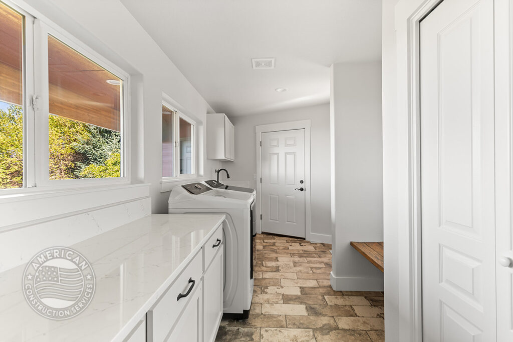 Laundry room with quartz counters and white cabinets remodeled by American Construction Services, Corp.