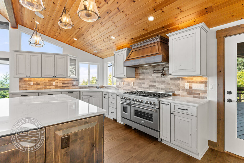 Kitchen with wood beam ceilings, white cabinets, island, stainless steel range and oven