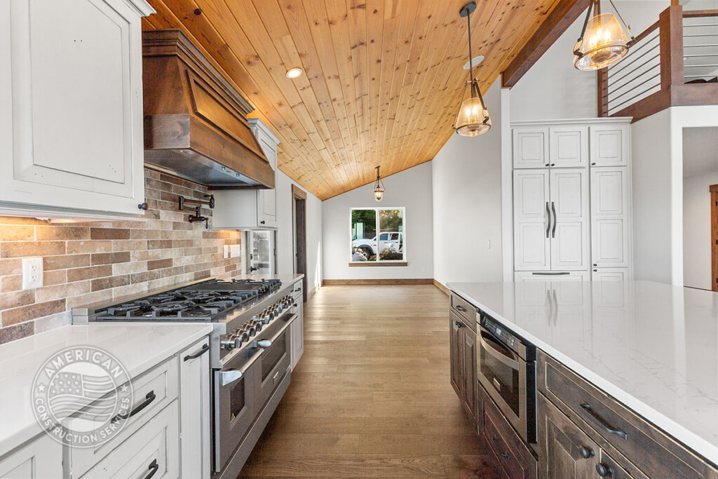 Kitchen and dining nook with vaulted wood beam ceiling, white custom cabinets, remodeled by American Construction Services, Corp.