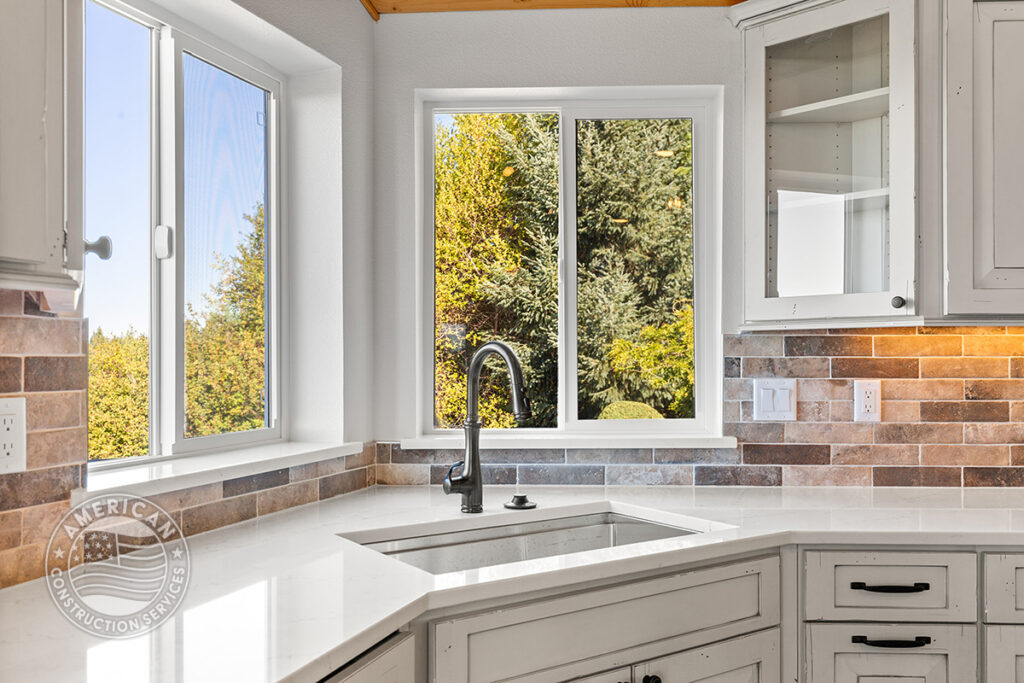 Remodeled kitchen with white custom cabinets, sink with territorial views out the window. Remodeled by American Construction Services, Corp.