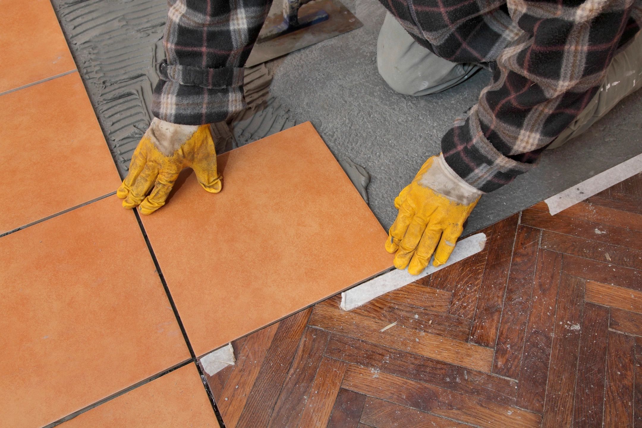 person with gloves on doing a flooring installation